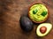 Avocado with guacamole sauce on a dark wood background. Half and