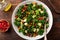 Avocado, kale, roasted chickpeas, almond and pomegranate salad in white bowl