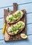 Avocado and labne toast with micro greens on a cutting board, top view. Good fats healthy eating