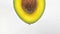 Avocado oil concept on white background. Avocado oil drips off half an avocado. Oil drop.