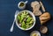 Avocado, romano, kumato tomatoes salad and whole wheat branny bread on blue background, top view. Healthy diet vegetarian food