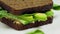 Avocado sandwich on dark rye bread made with fresh sliced avocado, spinach and cream cheese