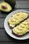 Avocado sandwich on dark rye bread made with fresh sliced avocados on dark background