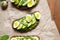 Avocado sandwich toast on dark rye bread made with fresh sliced avocados with spinach, guacamole, arugula and quail eggs