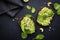 Avocado sandwich or toast on rye bread with spinach, crushed cashew nuts and sesame seeds, black table background, top view