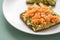Avocado smoked salmon on sunflower seed whole grain bread slice with sesame seeds for breakfast or snack on mint green background