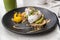Avocado toast with eggs breakfast plate at restaurant closeup. Trendy healthy morning food at cafe with guacamole and poached egg