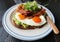 Avocado toast with sunny side up eggs topped with bacon.