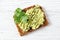 Avocado toast on whole grain bread, mashed avocado with sesame seeds and parsley, healthy eating concept, top view