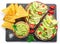 Avocado toasts, guacamole and tortilla chips on black slate serving plate. Flat lay