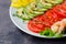 Avocado, tomato, pepper and shrimps on a plate lined with rows.