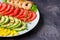 Avocado, tomato, pepper and shrimps on a plate lined with rows.