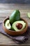 Avocado whole and halves in a wooden bowl