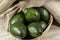 Avocados fruits on the wooden table, with jute and black background