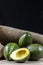 Avocados fruits on the wooden table, with jute and black background