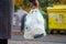 Aware woman separating paper from other waste, putting it into green container to save natural resources in Prague Chezh