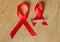 Awareness red ribbon and syringe on wooden background: world day of fight against AIDS, promotion public support for the