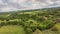 Awesome aerial view with green hills and meadows, oaks forest and agriculture fields planted with fruit trees with dramatic sky