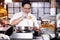 Awesome Asian chef standing in front of the frying pan and preparing order