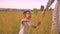 Awesome asian kid runs near his mother joyfully in countryside on yellow field