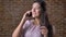 Awesome beautiful caucasian woman is touching her hair while talking over phone calmly, biting her lips and smiling