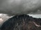 Awesome dark cloud at the top of the mountain. Wonderful dramatic landscape with big snowy mountain peaks above low clouds.