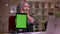 Awesome footage of caucasian blonde girl holding her tablet with green screen on it and smiling gracefully, happy mood