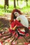 Awesome girl with freckles and red hair posing with a lowered red dress and bare shoulders on wild nature.