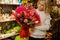 Awesome red bouquet of different flowers decorated with wrapping paper in hands of woman