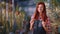 Awesome redhead gardener lady with a large smile looking straight to the camera and posing in the middle of industrial