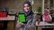 Awesome smiling arabic woman in grey hijab is demonstration green screen on her tablet while standing indoor, working