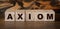 Axiom word on wood blocks. A row of wooden cubes with a word written in black