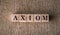 AXIOM word written on wooden blocks on a brown background
