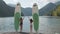 Axle view of two attractive sporty girls standing on coast with surfing boards. Beautiful fit woman waving hands