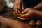 An Ayurvedic abhyanga massage in progress, showing hands rhythmically prepare herbal oils to a warm skin. Capture the rejuvenating