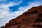 Azure blue sky and white wispy clouds backdrop the sharp ruggedness of desert sandstone