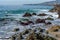 Azure waves crashing over colorful rocks in California