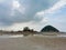 Aâ€‹ smallâ€‹ island with mountainâ€‹ and sea rocks onâ€‹ theâ€‹ low tide sandy beachâ€‹ with shallow water and cloudyâ€‹ skyâ€‹