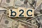 B2C business-to-consumer business relationship theme. wooden cubes with the acronym B2C, on the background of dollar bills. B2C