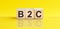 B2C - Business-to-consumer - word is made of wooden building blocks lying on the yellow table