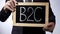 B2C, business-to-consumer written on blackboard, businessman holding sign