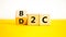 B2C or D2C symbol. Concept words B2C business to consumer D2C direct to consumer. Beautiful yellow table white background. B2C