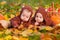 Babies twins in jackets with ears lie on plaid among autumn sheets, pumpkins and apples. One little girl gestures to secret,