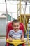 Baby 2 years riding on a swing. Happy child on the playground. ertical photo