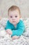 Baby 6 months in a blue sweater and striped shorts lying on the bed. Chubby cheeks small child portrait close-up. Girl boy