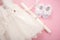 Baby baptism dress on pink background with cross, candle and baby shoes