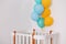 Baby bedroom interior. Minimalistic baby room interior. Festive balloons in front of baby bed. Baby birthday celebration concept.