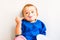 Baby with bib enjoying while eating a yogurt with spoon and stains