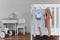 Baby bodysuit with zebra and dog face on hanger on bed, beige background. Cute children& x27;s clothes, baby chair