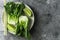 Baby bok choi halves, limes, chopsticks on gray background. Top view, horizontal orientation with copy space